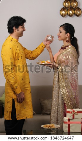 Good looking husband performing Karwa Chauth traditions of offering water to her fasting wife in traditional wear. Royalty-Free Stock Photo #1846724647