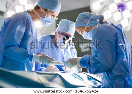 A team of surgeons carefully performing an operation with use of precision tools in the operation theatre Royalty-Free Stock Photo #1846752424