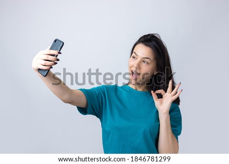 Portrait of a pretty girl taking a selfie isolated over grey background