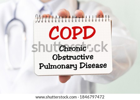 Doctor holding a card with text COPD Chronic Obstructive Pulmonary Disease, medical concept. The text is written in blue letters in a medical journal.