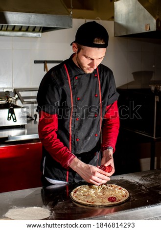 
Pizza cooking concept, chef puts ingredients on pizza