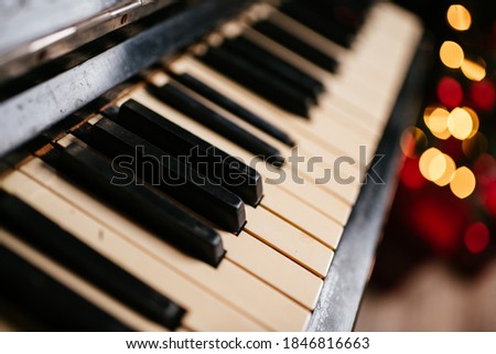 New Year 2021 interior with candles, bulbs and bokeh. Room decorated to christmas celebration. Christmas tree with presents. Old Piano keys