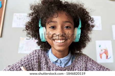 Happy african american mixed race kid child girl wearing headphones looking at camera or web cam remote distance learning on video zoom conference call, virtual class, headshot close up face portrait. Royalty-Free Stock Photo #1846820119