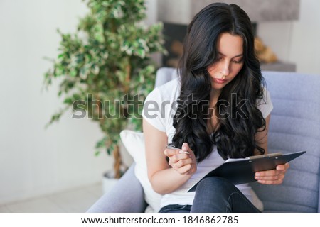 Portrait of a young woman in the office. Woman writes data to the questionnaire.