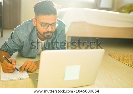 distance home learning concept indian male doing home work in living room business start up