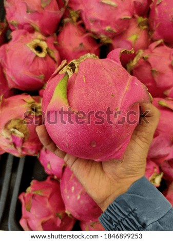 Hand holding fresh Dragon Fruit is sold in a supermarket.Shot were noise and film grain in full resolution.