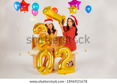 Buddies,portrait asian beauties in sandy dresses,celebrating the New Year party holding gold number balloons 2021, celebrating the New Year's holiday of the charming model Happy New Year and Christmas