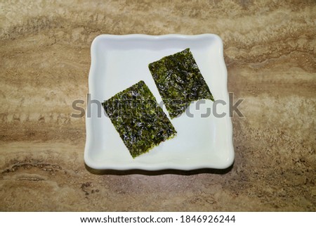 Two nori sheets, edible red algae or seaweed on a plate.