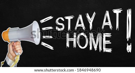 A businessman speaks into a loudspeaker, next to the text - STAY AT HOME. No face visible. Black background