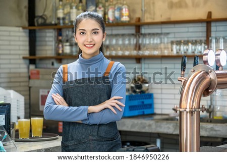 Portrait Asian Small business owner doing Hands crossed and looking at camera for Welcome Open behind her counter in a pub,Successful proud young brewer at his pub with copy space,Small business owner