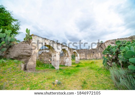 panoramic view of the interior of a huge ruined hacienda with no roof and full of vegetation