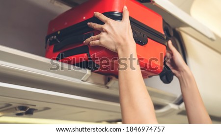 Cabin crew lift luggage bag in airplane . Airline transportation and tourism concept. Royalty-Free Stock Photo #1846974757