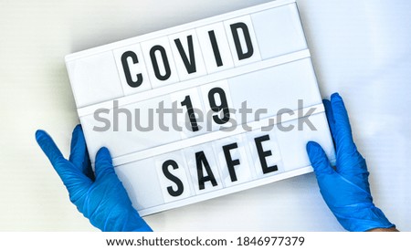 Doctor in protective gloves holding Lightbox with text COVID 19 SAFE. Back to school. Social distancing. School quarantine concept. Copy space. Coronavirus second wave