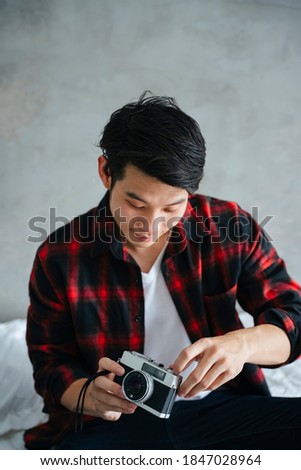 Asian young man checking film camera before going outside.