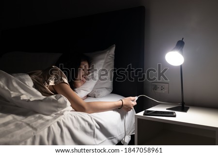 Asian child girl resting on the bed,turning off the light switch before bedtime to sleep in the bedroom at night,turn off lights when not in use,hand turning off lamp,energy power saving , save money Royalty-Free Stock Photo #1847058961