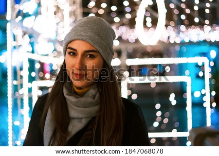 Beautiful young woman at christmas market smiling at camera