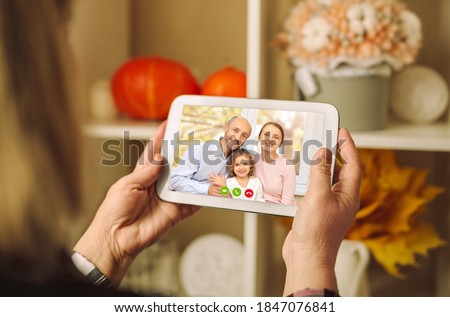 A happy family is having a thanksgiving dinner and saying cheers to their parents on a video conference call, Lockdown condition Royalty-Free Stock Photo #1847076841