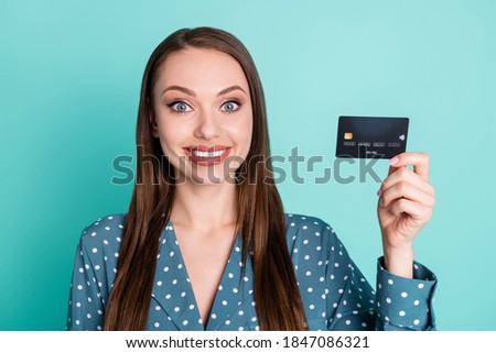 Portrait of positive cheerful girl hold credit card wear blue polka-dot blouse isolated over turquoise color background