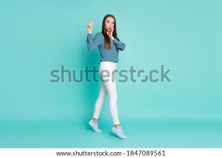 Full length profile side photo of astonished girl go look in camera make v-sign isolated on turquoise color background