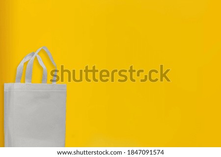 White Color Non Woven Fabric shopping bag with yellow background. Copy space for text and logo. Sale banner concept. 