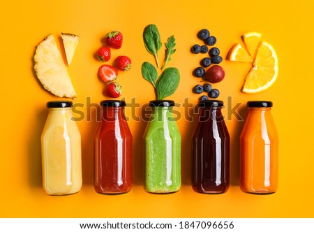 Flat lay composition with bottles of delicious juices and fresh ingredients on orange background Royalty-Free Stock Photo #1847096656