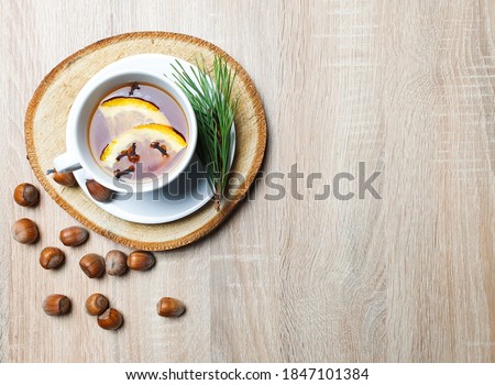 Autumn still life. Copy space mockup of an autumn composition with warm tea and hazelnuts on a wooden background. Fall and Thanksgiving concept. Styled stock flat lay photo. Top view, vertical.