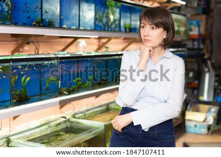 Portrait of pensive woman visiting pet store in search of exotic aquarium fish