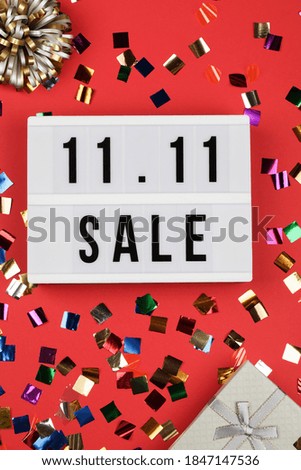 11.11 sale text on white lightbox, holiday ribbon and box on red background. Online shopping, singles day sale concept. Top view copy space 