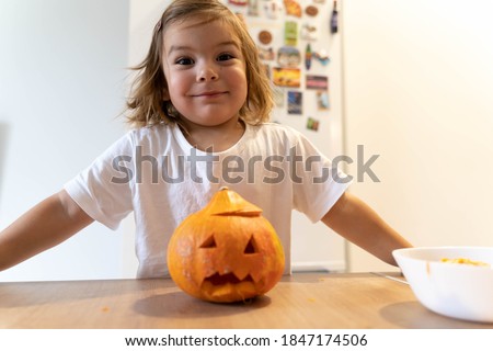 Happy toddler child with carved pumpkin at home. Halloween activities with kids