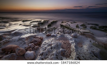 Calm ocean long exposure. Stones in mysterious mist of the sea waves. Concept of nature background. Sunset time on the beach. Sunlight on horizon line. Soft focus. Balangan beach, Bali, Indonesia. 