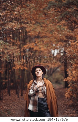 Outdoor fashion photo of young beautiful lady in autumn landscape with dry grass. Knitted sweater, wine lipstick. Warm Autumn.