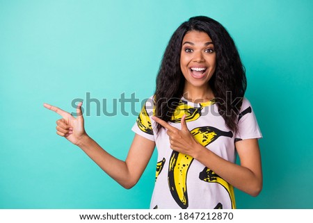 Photo of young black girl open mouth indicate fingers empty space wear banana print t-shirt isolated turquoise color background
