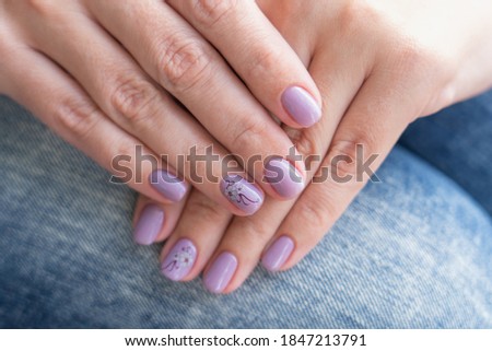 Closeup top view photography of two beautiful manicured female hands with trendy professional long lasting pastel purple painted nails with modern gel nailpolish