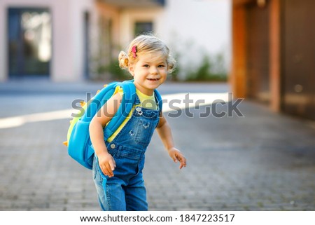Cute little adorable toddler girl on her first day going to playschool. Healthy beautiful baby walking to nursery school and kindergarten. Happy child with backpack on the city street, outdoors. Royalty-Free Stock Photo #1847223517