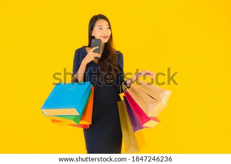 Portrait beautiful young asian woman with shopping bag credit card and smart mobile phone yellow isolated background