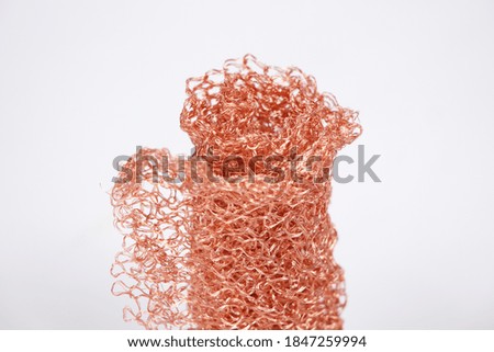 Photo of rolled red metal knitted grid on white background
