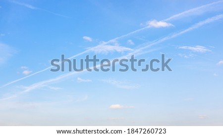 low contrail and little cumuli clouds in blue sky on autumn day Royalty-Free Stock Photo #1847260723