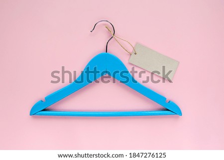 Wooden blue hanger with black paper label isolated on pink paper background. Clothing tag, label blank mockup template, to place your design. Black friday final sale banner