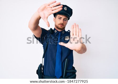 Young caucasian man wearing police uniform doing frame using hands palms and fingers, camera perspective 