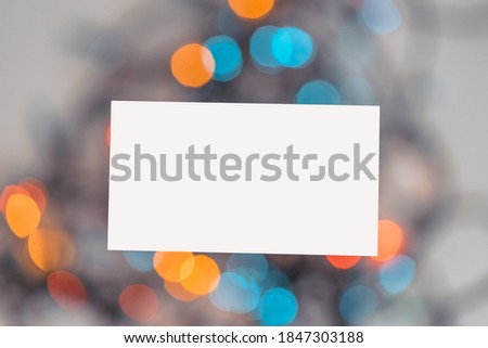 Blank White Business Card On Christmas Garland Light Background. Stationary For Branding Identity. Creative Templates For Office Corporate Style. Card For Congratulations. Bokeh