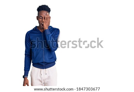 Young african american man wearing sportswear yawning tired covering half face, eye and mouth with hand. face hurts in pain. 