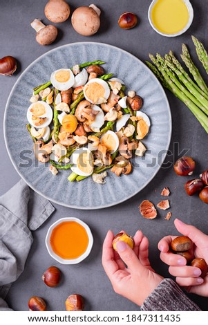 Salad with chestnuts, mushroom, asparagus and eggs on grey stone background, top view, autumn dish, flat lay