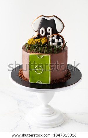 Birthday cake on the football theme on the white background. Gingerbread cookies in a shape of soccer ball, boot and T-shirt.
