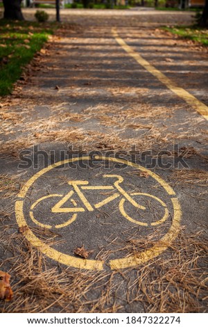 Bicycle path in the autumn park with yellow paint applied to the asphalt