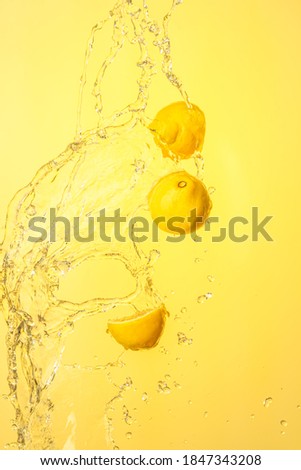 Lemon halves splashing in mid air against yellow background. Splash photography background