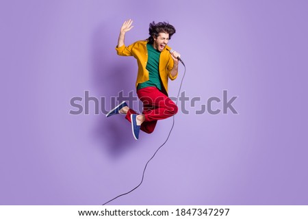 Photo portrait full body view of guy shouting singing into mic jumping up isolated on vivid purple colored background Royalty-Free Stock Photo #1847347297