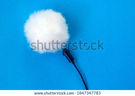 Lavalier small microphone and wind protection blue background.