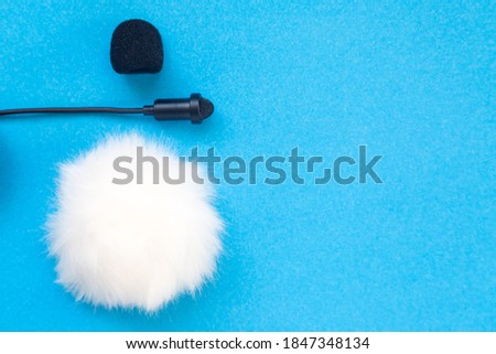 Lavalier small microphone and wind protection on blue background.