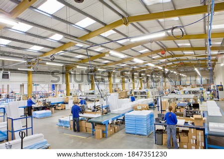 A high angle wide shot of workers on a production line in an aluminum light fittings factory. Royalty-Free Stock Photo #1847351230