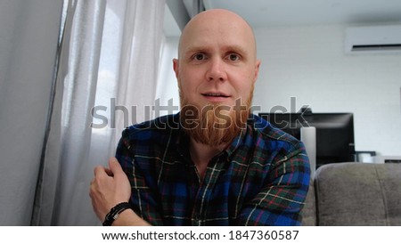 A young bald Caucasian man with a red beard communicates with interest via video chat. Online conversation. Royalty-Free Stock Photo #1847360587